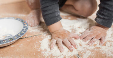 Toddler hands playing with flour sprinkled on the floor. Os Tartarouchos/Getty Images