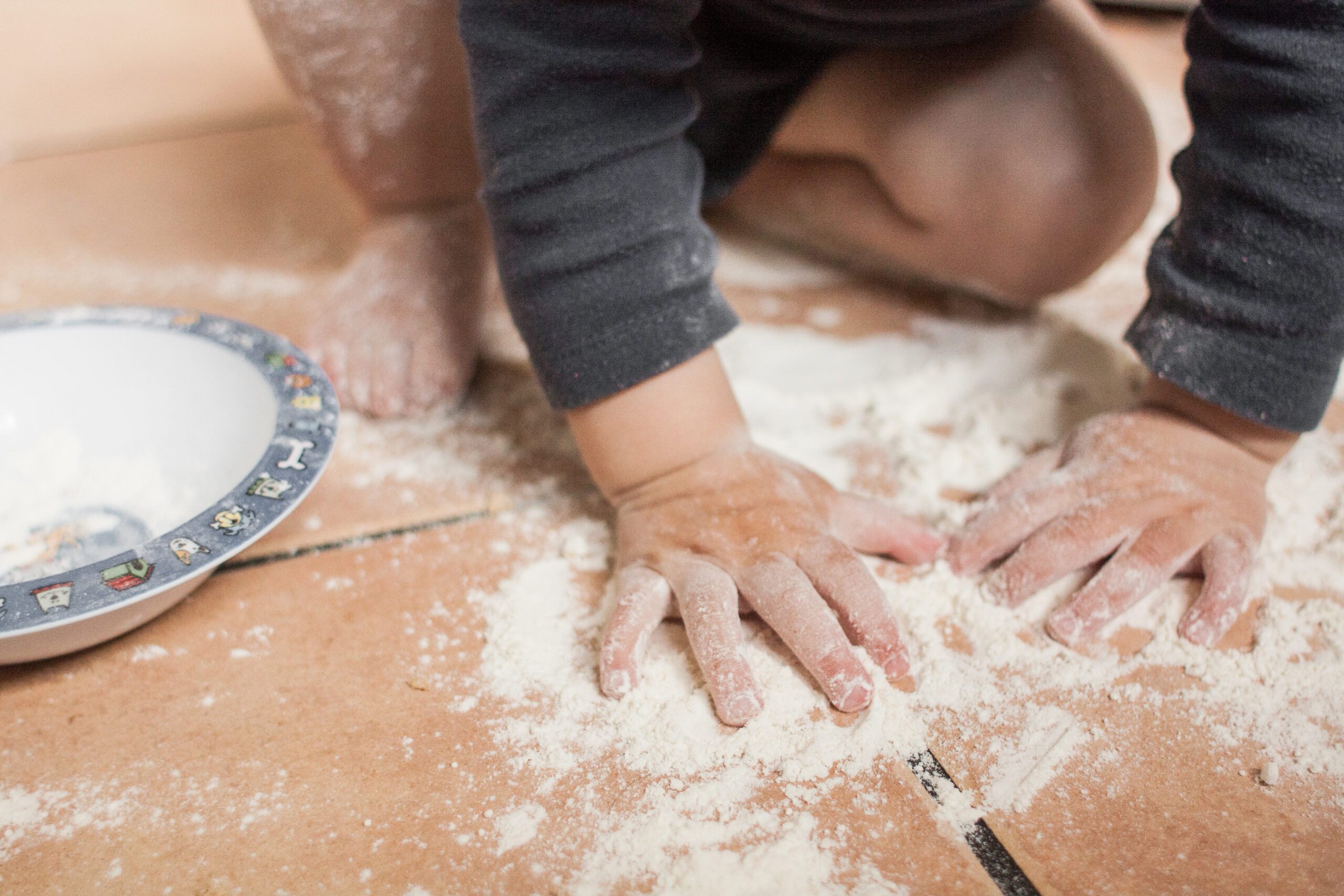 Toddler hands playing with flour sprinkled on the floor. Os Tartarouchos/Getty Images